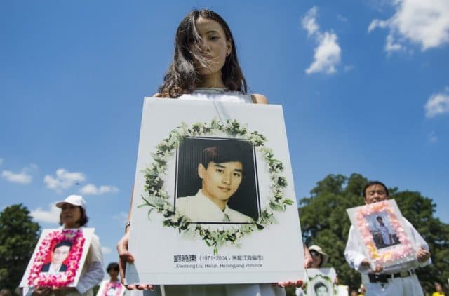Falun Gong demonstrators hold memorial pictures as they march on Capitol Hill in Washington, DC, July 17, 2014, as part of the events sponsored by the Falun Dafa Association of Washington, DC, to end "Chinese persecution of Falun Gong practitioners".       AFP PHOTO / Jim WATSON (Photo by JIM WATSON / AFP)
